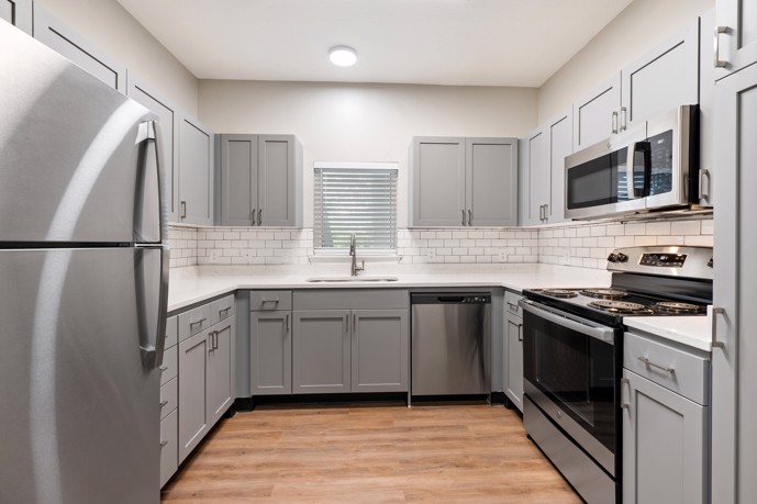 A well-appointed U-shaped kitchen featuring subway tile, stainless steel appliances, and hardwood-style flooring.